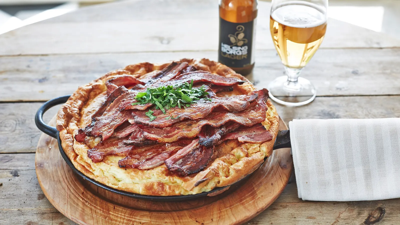Skånsk äggakaga med krispigt bacon och gräslök på träbricka